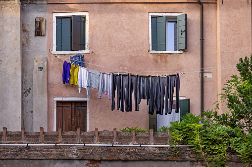 Venice, Italy - October 6th 2022: Laundry put out to dry in the late afternoon sun in a narrow street in the center of Venice