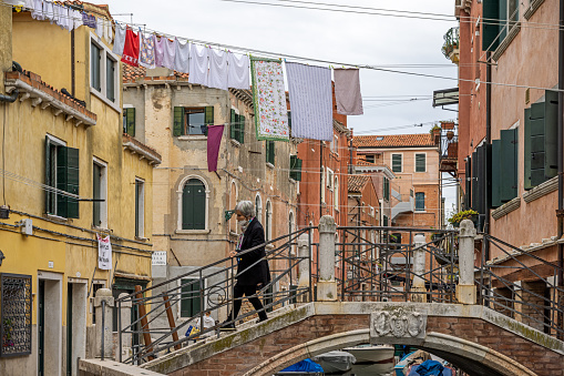 Romantic couple kissing while standing on arch footbridge over Grand Canal between historic residential buildings at Venice,Italy