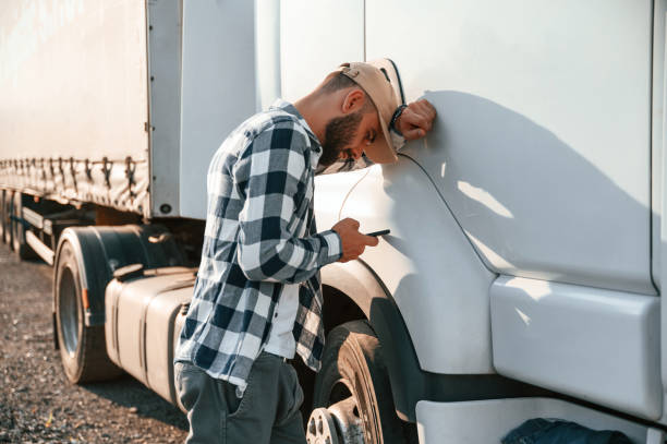 istock Feeeling tired. Using smartphone. Young truck driver is with his vehicle at daytime 1436157927