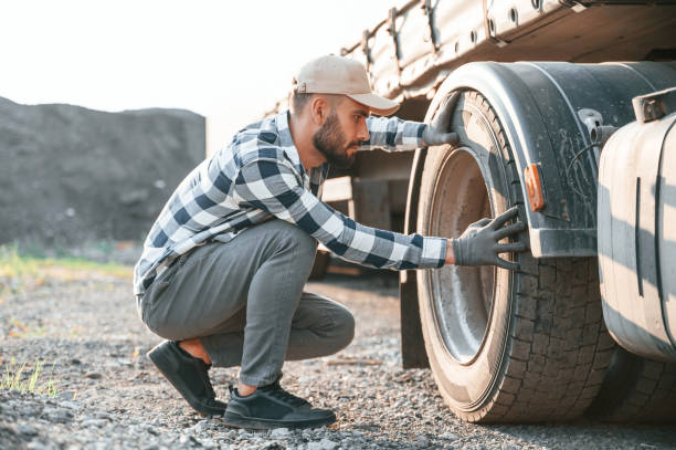 istock Testing the tires. Young truck driver is with his vehicle at daytime 1436158321