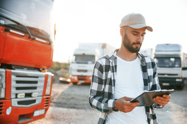 istock Looking at document in notepad. Young truck driver is with his vehicle at daytime 1436159097