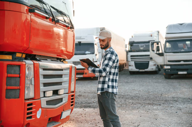 istock Looking at document in notepad. Young truck driver is with his vehicle at daytime 1436159107