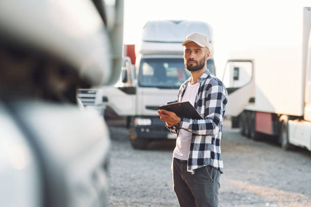 istock With black notepad. Young truck driver is with his vehicle at daytime 1436159554