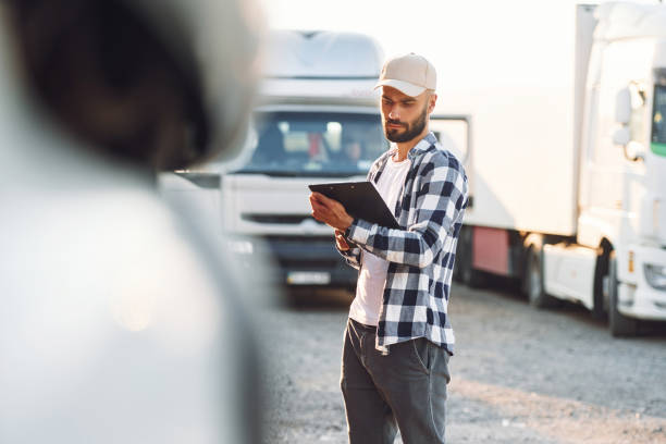 istock With black notepad. Young truck driver is with his vehicle at daytime 1436159563