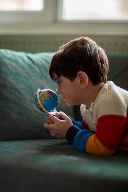 istock Young boy looking at globe in bedroom 1436159773
