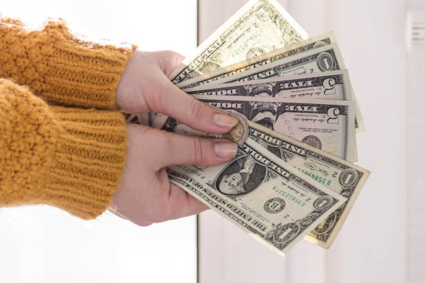 黄色いセーターを着た女性の手には、小さなドル紙幣が握られている。 - human hand beak currency stack ストックフォトと画像