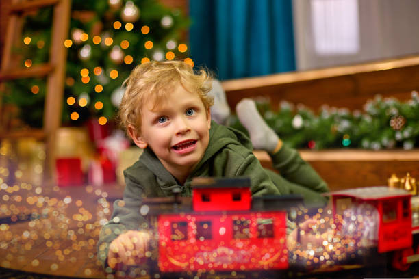 istock Cute curly-haired boy is playing with a magic toy train at the Christmas tree. 1436161781