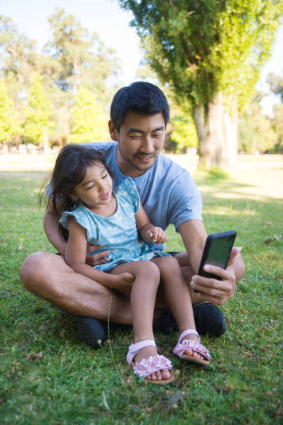 istock Asian daddy taking picture with his little kid in summer park 1436163466