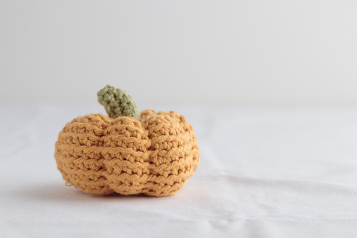 Cute crochet knitted yellow pumpkin on white background with a copy space