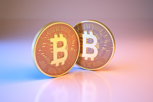 Moneda digital Bitcoin sentada sobre fondo azul metálico y rosa photo