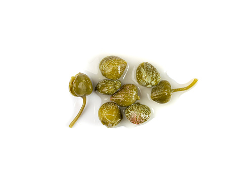 Pickled capers pile isolated. Marinated caper buds, small salted capparis, fermented food, pickled capers group on white background top view