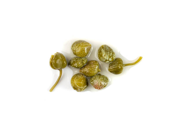 Pickled Capers Isolated. Marinated Caper Buds, Small Salted Capparis Pickled capers pile isolated. Marinated caper buds, small salted capparis, fermented food, pickled capers group on white background top view caper stock pictures, royalty-free photos & images