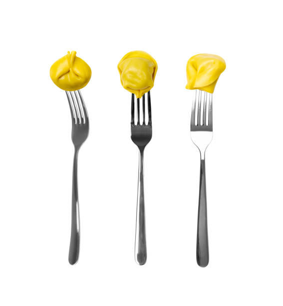 Tortellini on forks isolated. Agnolotti, cappelletti, italian dumplings, stuffed pasta on fork, yellow tortelloni, handmade ravioli, cappelletti on forks, uszka on white background