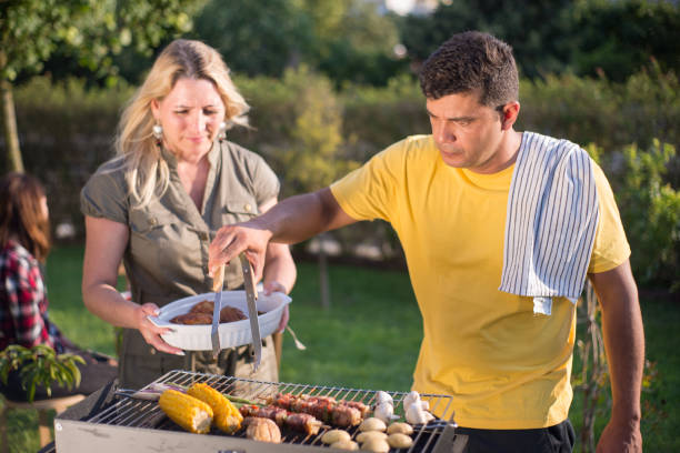 istock Happy husband and wife making BBQ in backyard on sunny day 1436171710