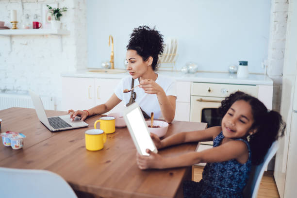 istock Mother and daughter using gadgets at breakfast 1436171856