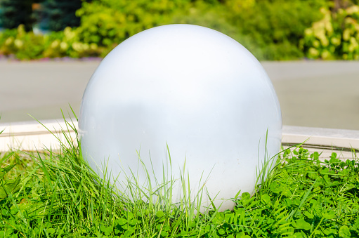 Elements of landscape design in the park. White glass balls. landscape garden lamp ball. Outdoor lamp in the shape of a ball for artificial lighting of recreation areas, local area and city parks.