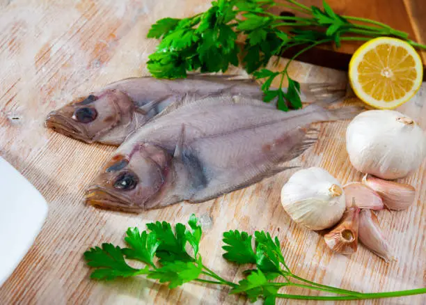 Raw fresh rooster fish before cooking on wooden desk, nobody