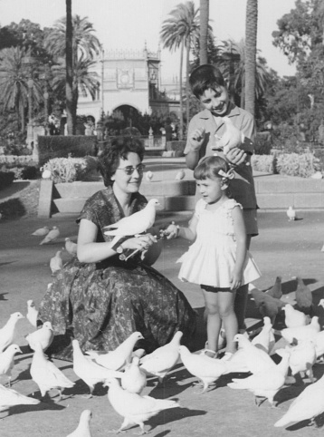 Image taken in the early 60s: woman and her children playing with pigeons