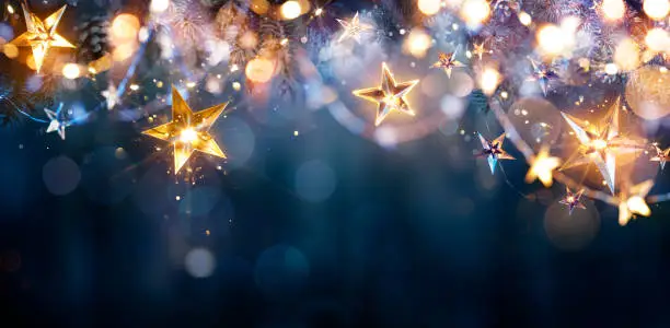 Photo of Christmas Lights - Stars String Hanging At Fir Branches In  Abstract Defocused Background