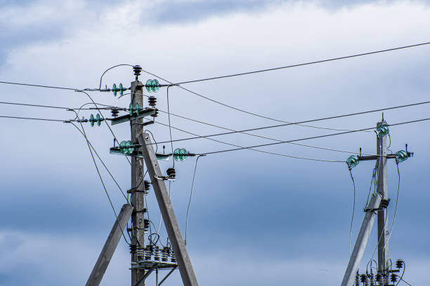 postes de alta tensão em fundo de céu nublado. - overhead wires - fotografias e filmes do acervo