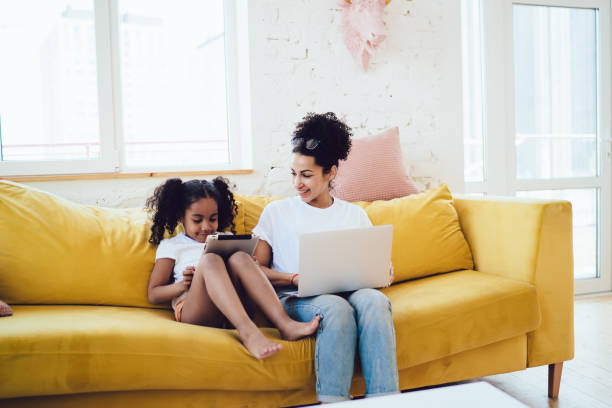 istock Smiling black mother looking at daughter with tablet 1436176227