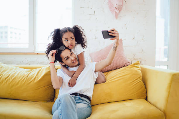 istock Mother and child taking picture with phone on sofa 1436176231