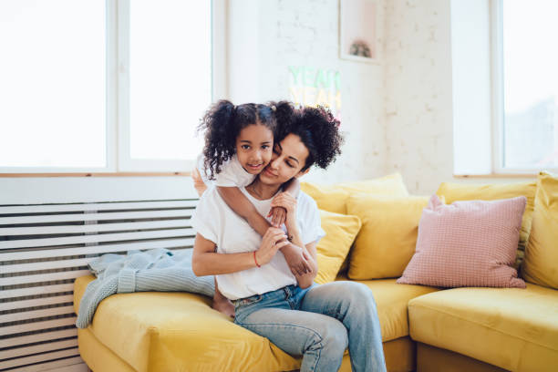 istock Embracing mother with daughter on bright couch in flat 1436176252