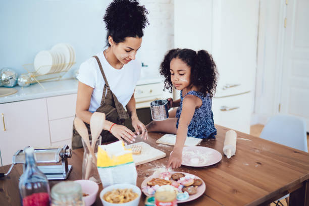 istock Daughter sitting on table near mother and wanting cookie 1436176268