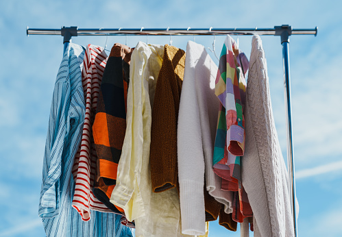 Low angle view at colourful clothes hanging on rail against blue sky.