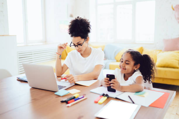 istock Mother working on laptop and daughter playing on smartphone 1436182404