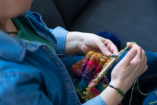 Mature woman knitting wool at home