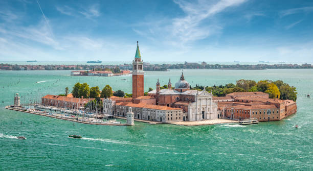 Panoramic view of San Giorgio Maggiore Island with church, Venice, Italy. Island with church, bell tower, buildings and small marina or harbor. View from mainland Venice, Italy, Europe. Blue sky. san giorgio maggiore stock pictures, royalty-free photos & images