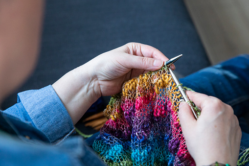 Closeup of senior woman hands knitting colorful blanket by hand