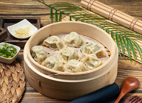 Steamed Dumplings with Leek with wood spoon and napkin served in a wooden dish side view of taiwan food