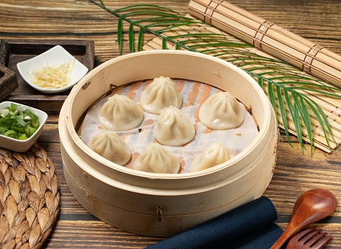 Xiao Long Tang Bao with wood spoon and napkin served in a wooden dish side view of taiwan food