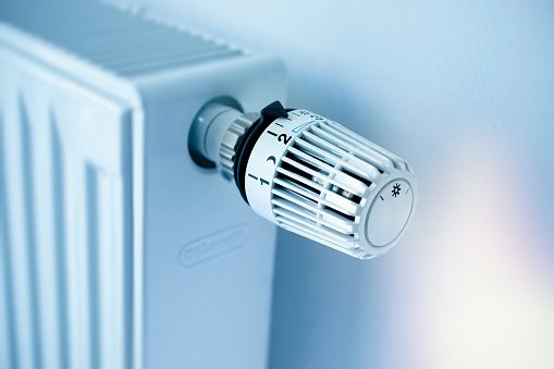 White panel radiator with a modern thermostat on the wall in an apartment - selective focus