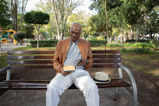 older man sitting on a bench reading a book