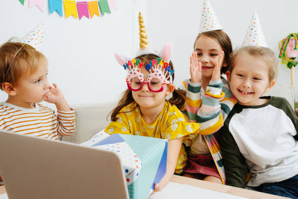 chatting on video call little kids in party hats gathered around a laptop - birthday child celebration party imagens e fotografias de stock