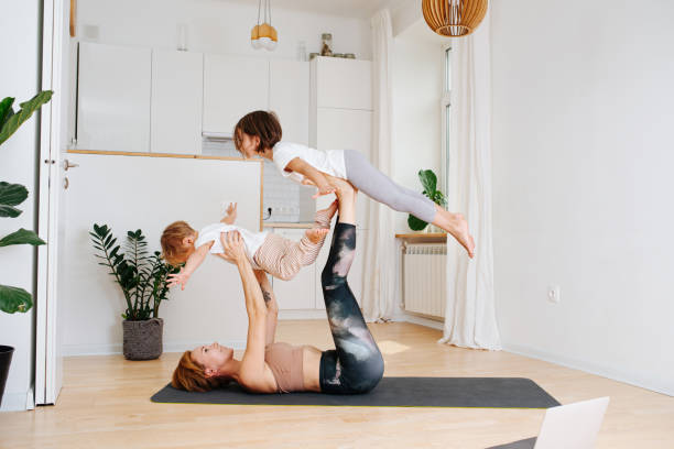 istock Fit happy young mom doing gimnastics with her kids. Lifting them both 1436196430