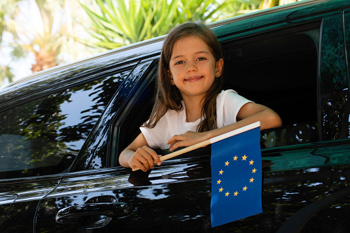 Girl holding EU Flag in the car.