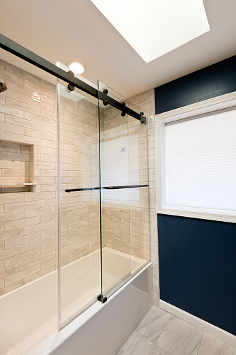 A contemporary modern bathroom design. featuring a glass enclosed bathtub