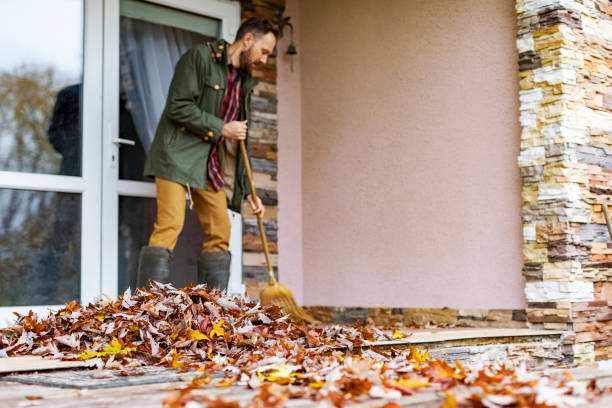 Adult man sweeping leaves from porch using broom