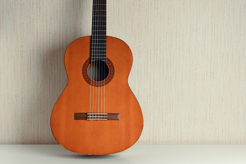 Classical acoustic guitar on a light wall background.