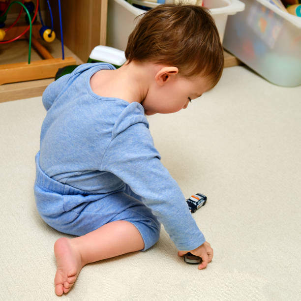 maluch bawi się samochodzikami na podłodze w domowym pokoju. dziecko bawi się zabawkami w przedszkolu. dziecko w wieku jednego roku i trzech miesięcy - hands and feet flash zdjęcia i obrazy z banku zdjęć