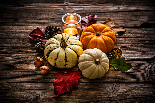 Autumn or Thanksgiving decoration: overhead view of gourds, dry leaves, burning candle, pine cones shot on rustic wooden table. High resolution 42Mp studio digital capture taken with Sony A7rII and Sony FE 90mm f2.8 macro G OSS lens