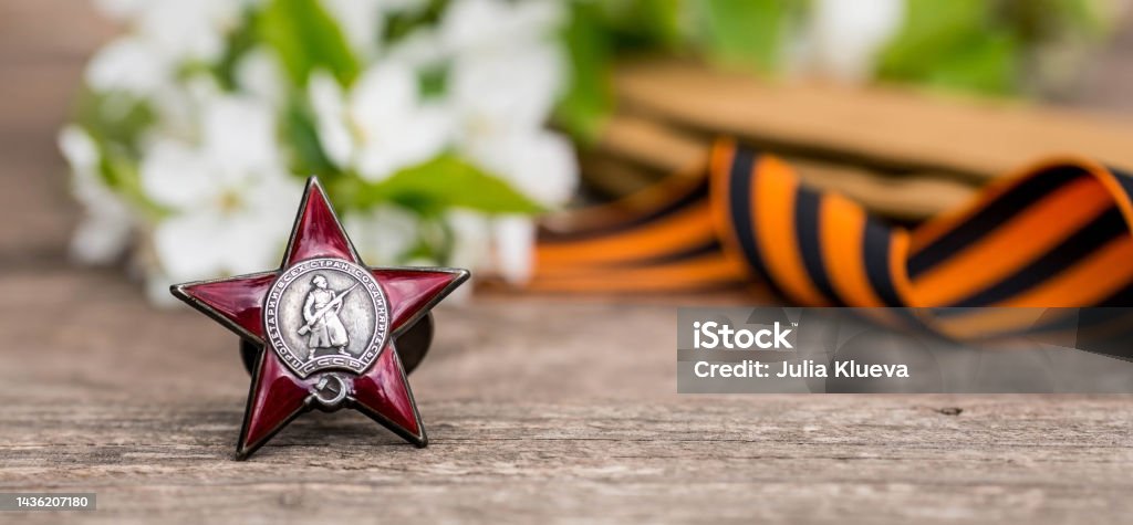 St. George's ribbon and the Order of the Red Star of the USSR World War II veteran on a wooden background. Translation into Russian: Workers of all countries unite. The concept of the May 9 holiday. History. The holiday is May 9th. Victory over fascism in 1945. The war with Germany. The Second World War. Veteran Stock Photo