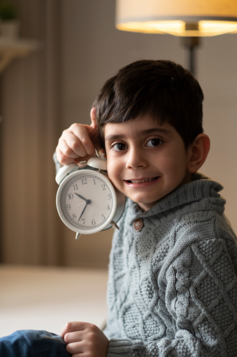 Joyful little boy with showing an alarm clock