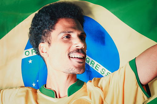 Brazilian Football Fan - Black Man Holding Brazil Flag Behind Celebrating