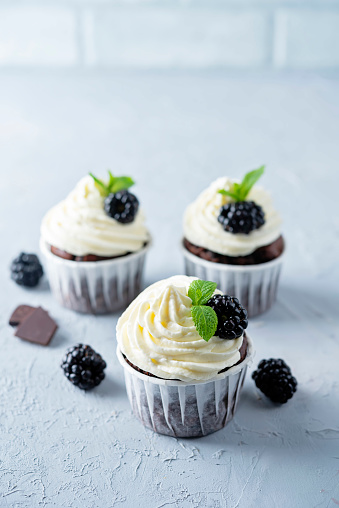 Chocolate banana cupcakes with cream cheese frosting and blackberries. toning. selective focus
