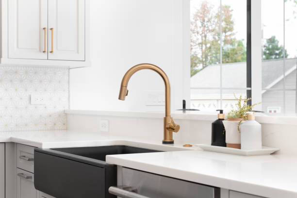 a kitchen sink detail shot with a gold faucet and black farmhouse sink. - sink imagens e fotografias de stock